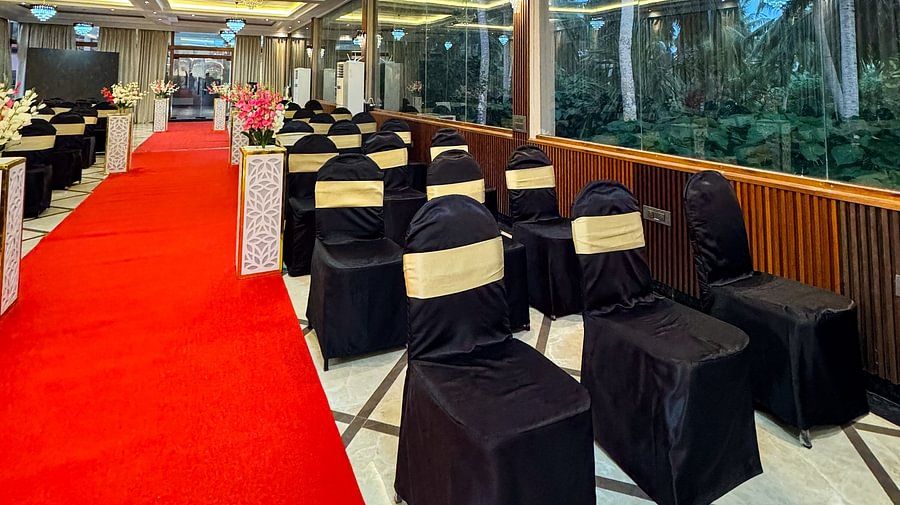 A hall with rows of black and gold chairs, a red carpet, and chandeliers at Silver Sand Sea Princess Beach Resort, Port Blair.