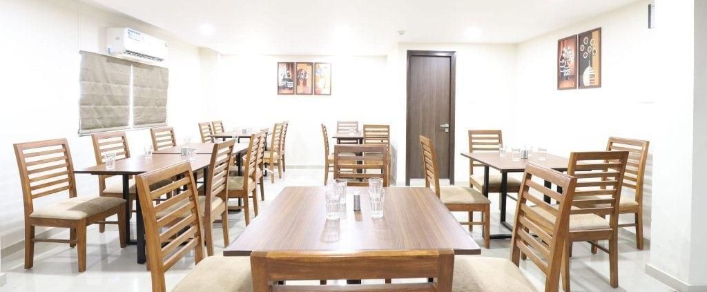 Side-angle view of a dining table with 2 chairs placed opposite to one another at Aranaya Restaurant at Pravasa Stay, Ahmedabad (Alba Premier).