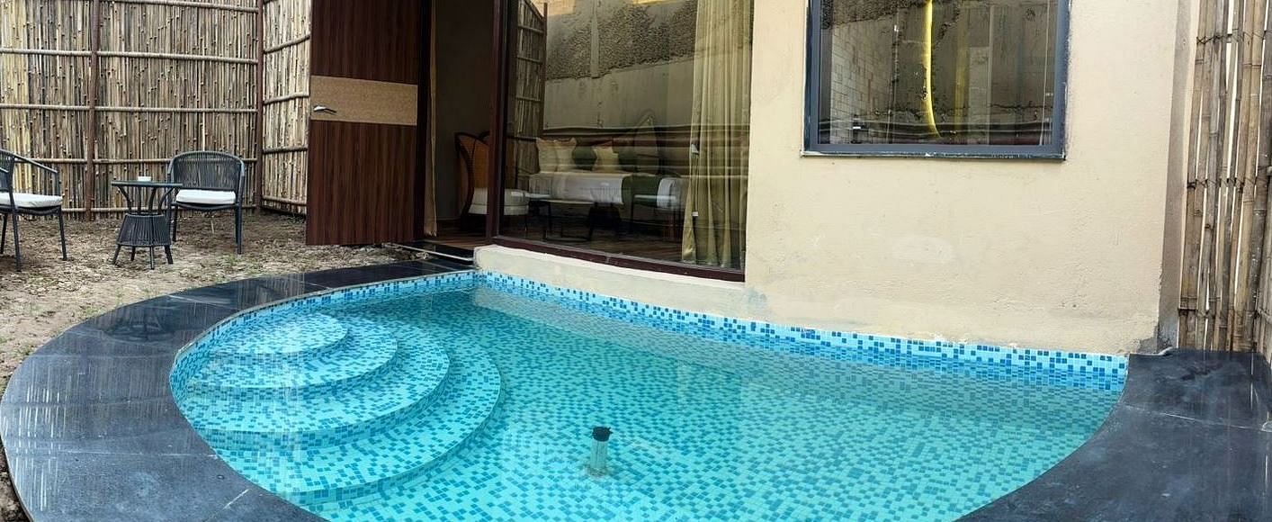 Luxury Villa with Plunge Pool featuring a private outdoor pool with steps leading into the water is surrounded by dark stone and lush greenery at The Qualia Resort Club & Brewery, Udaipur.