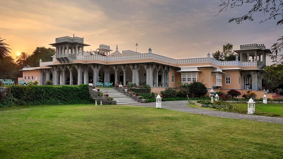 facade image of dev shree, deogarh with a beautiful lawn in the foreground and a picturesque sunset in the background