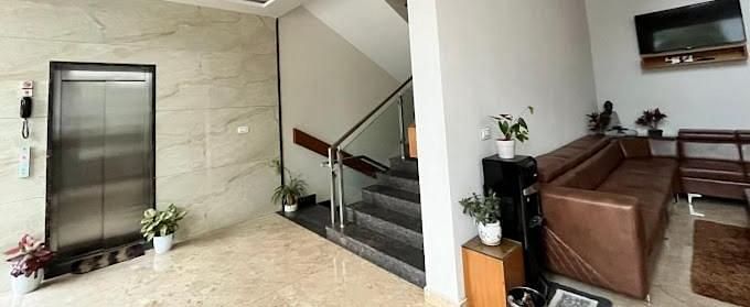 Reception area featuring with a staircase, a brown sofa, and wooden accents.- Sukhi - A Luxury Stay Inn, Chikkamagaluru