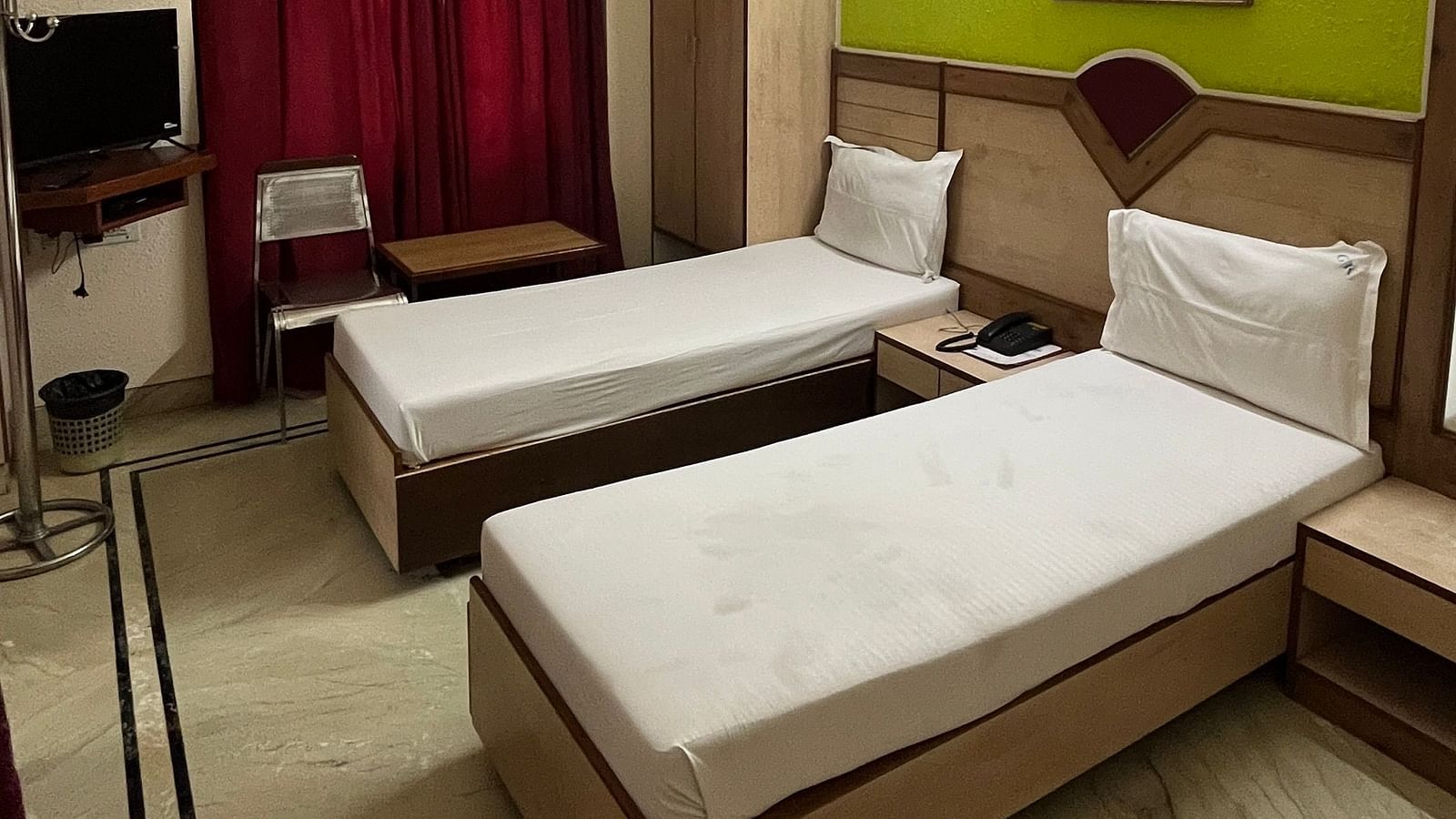 image of the superior room featuring a twin bed with plain white sheets spread at The Grand Krishna Rooms, Bengaluru