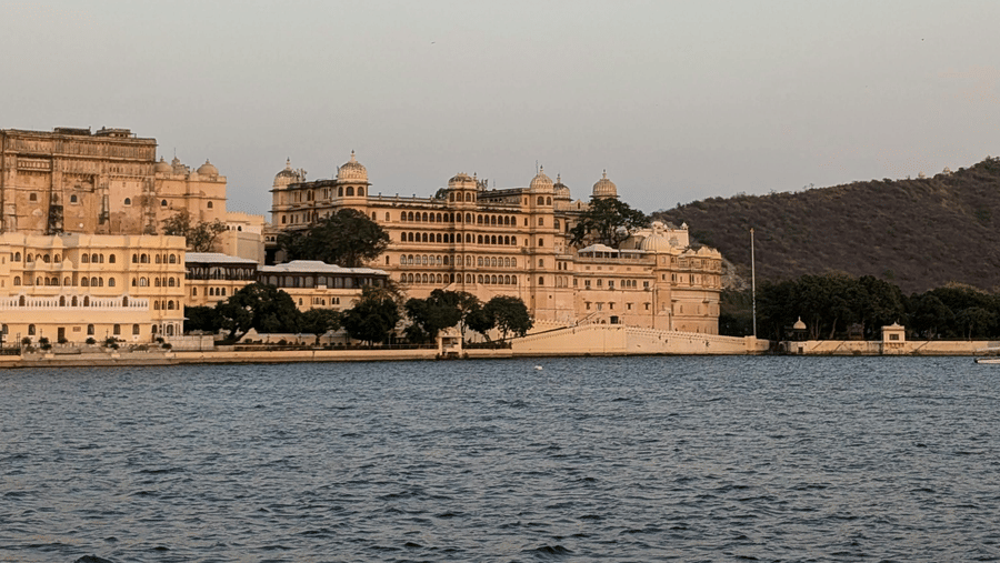 A view of a lake with distant palaces and hills, showing the expanse of water near historic areas.