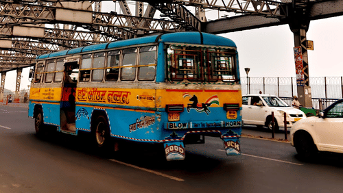 Colourful public bus crossing Howrah Bridge in Kolkata.