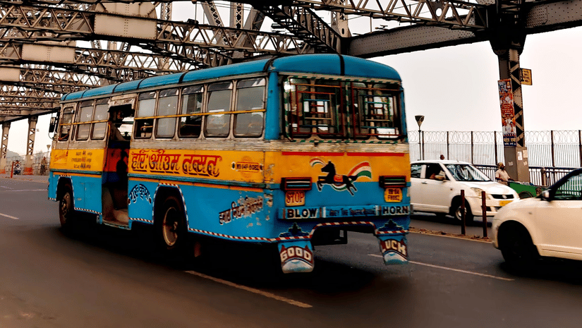 Colourful public bus crossing Howrah Bridge in Kolkata.