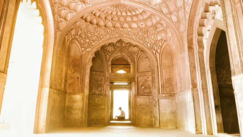 An interior shot of an ancient domed structure with intricate patterns on the ceiling, leading to a bright opening.