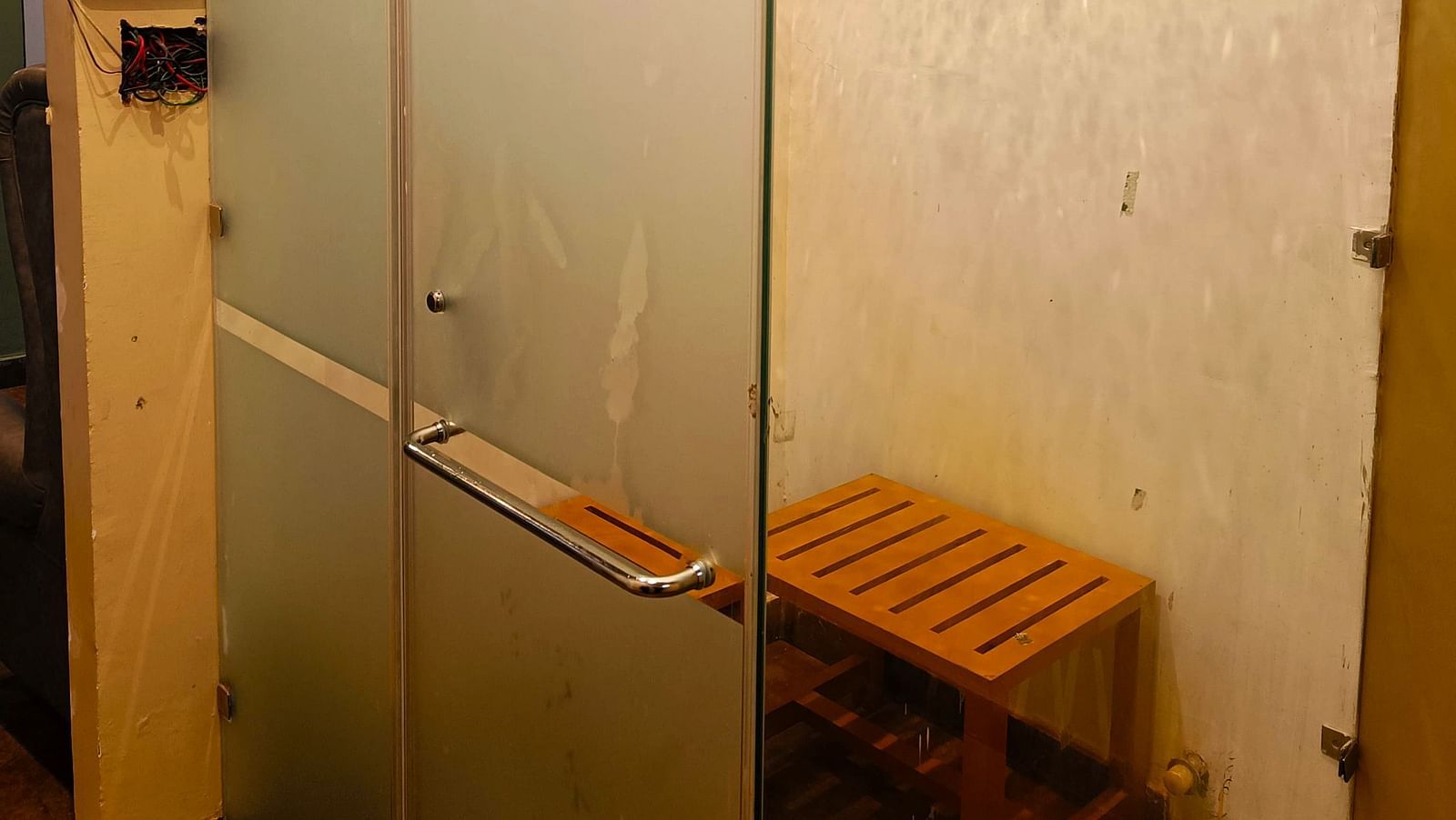 Glass-panelled room at DLS Forest Vines Resort featuring a wooden stool inside.