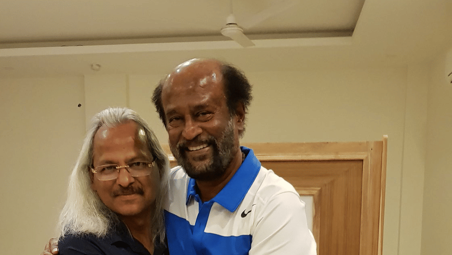 Rajnikanth, a tamil movie superstar, hugging the owner of Shaheen Bagh and posing for a picture inside a room.