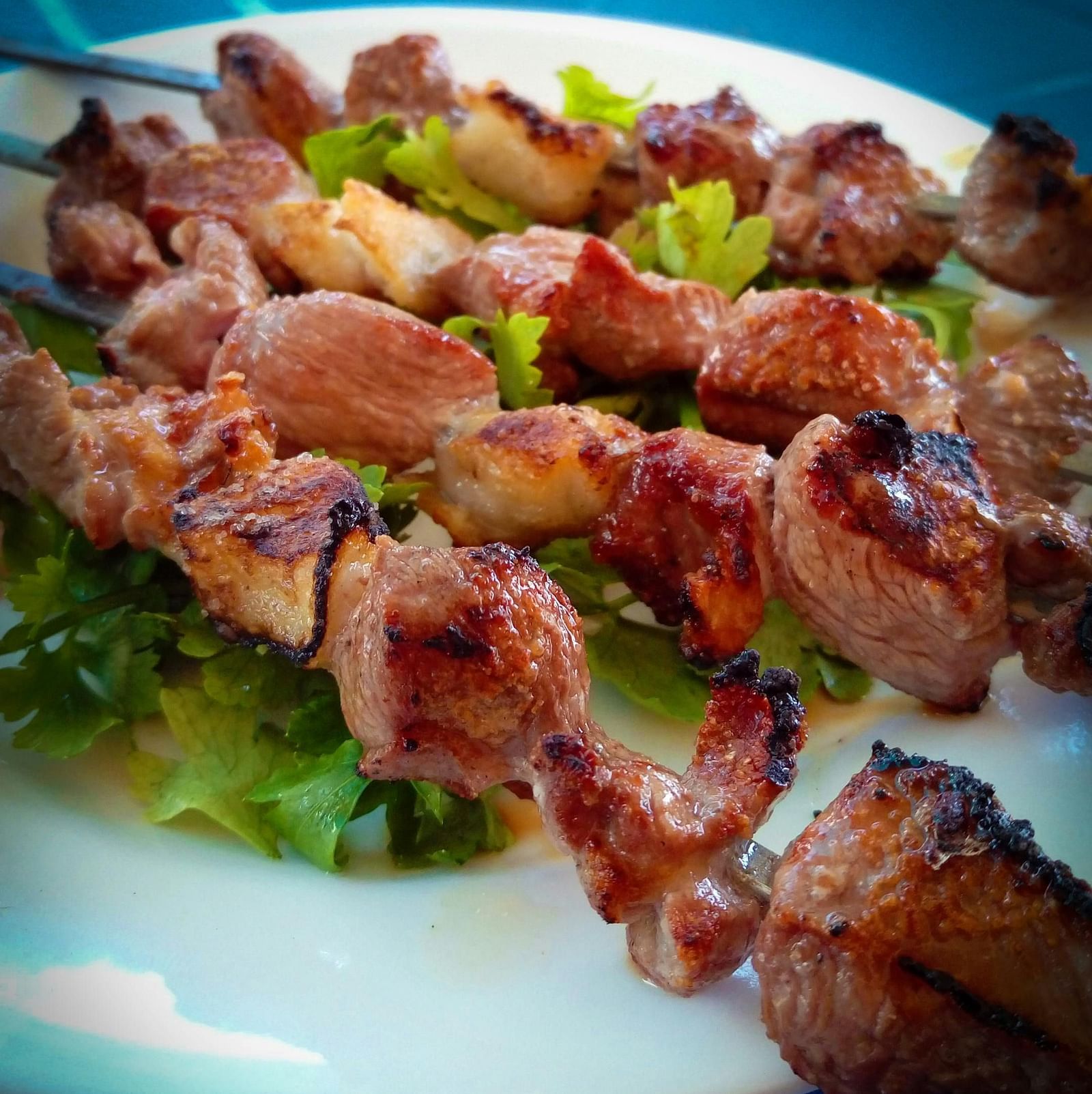 Assorted plate of barbecue chicken skewers loaded with lettuce.