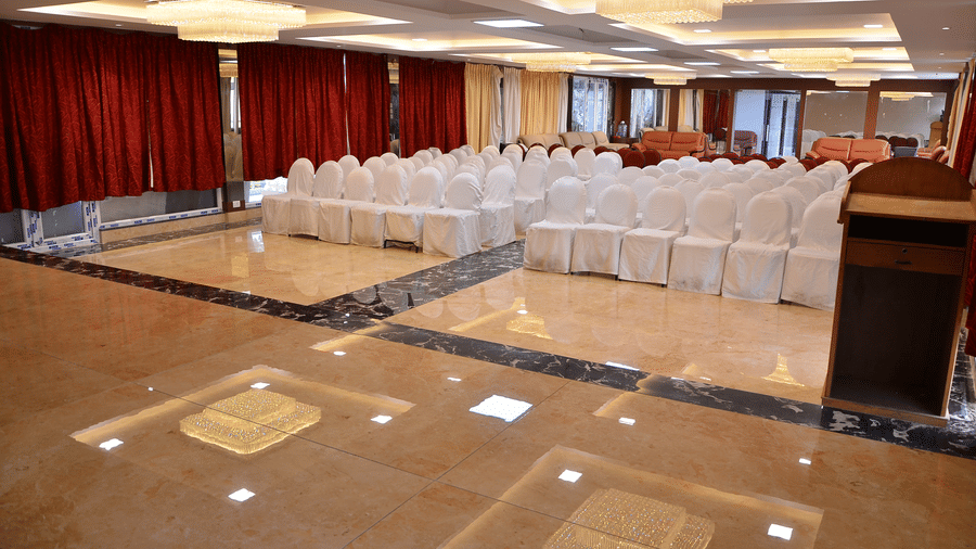 A spacious banquet hall with a stage setup and ample seating for formal gatherings and events - Benzz Park, Kodaikanal