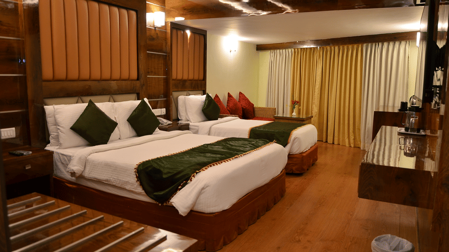 A family room with twin beds, stylish decor, and green accent cushions for a comfortable experience - Benzz Park, Kodaikanal