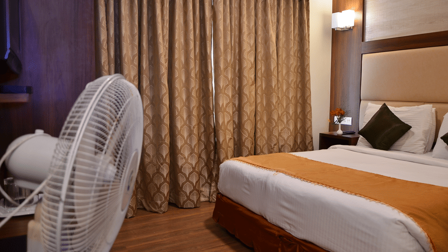 A neatly designed room with a single bed, curtain backdrop, and pedestal fan for added comfort - Benzz Park, Kodaikanal