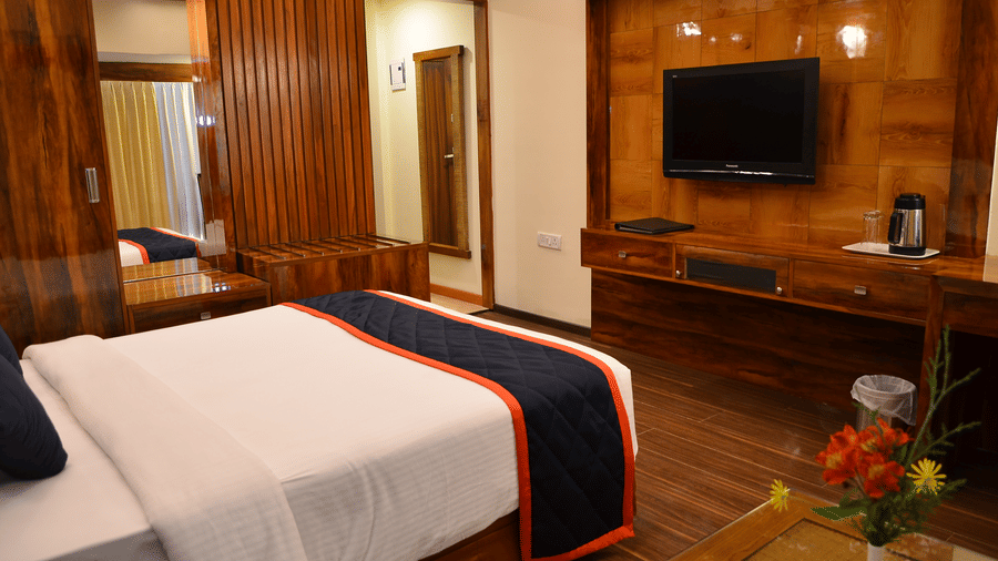Executive Room with a king bed, warm wooden interiors, and a flat-screen TV at Benzz Park, offering a cozy and comfortable stay for guests.