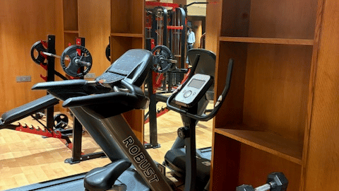 The gym's cardio section showing a treadmill, stationary bike, and a rack of dumbbells - Praveg's Grand Eulogia, Ahmedabad