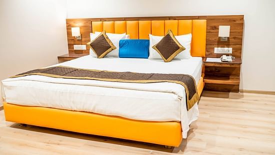 King size bed with a bedside table in the Suite With Breakfast at Kyriad Hotel, Gulbarga.