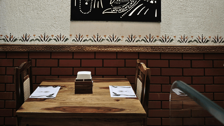 Close-up of a framed artwork hanging above a wooden dining area.