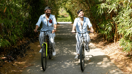 Two men riding bicycles amidst lush greenery - Karma Lakelands.