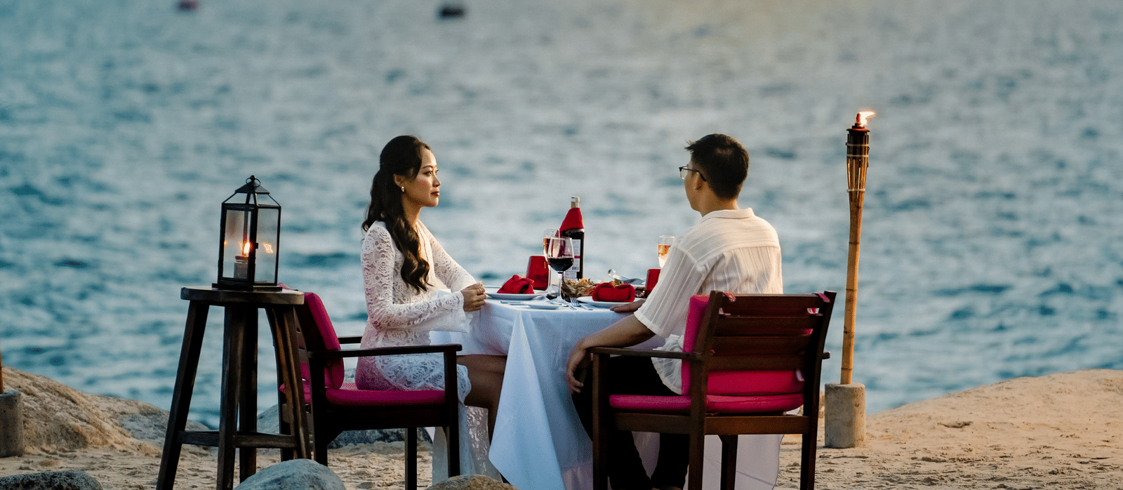 Dining setup at Alibu Resort in Vietnam, featuring a couple by the beachside enjoying their dinner.