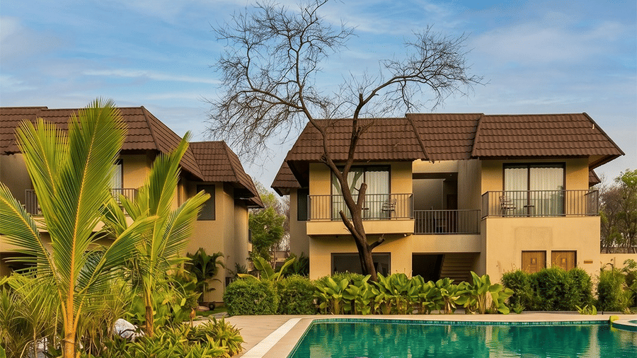 Inflatable pink flamingo float in swimming pool water with tropical plants, green trees, and brown roof villa buildings at Jivana Wellness Retreat.