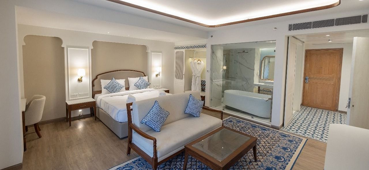 Full view shot of the Purna Room at Bhagirathi by RDB Atishay featuring a double bed and a couch in front of it at Bhagirathi by RDB Atishay. 