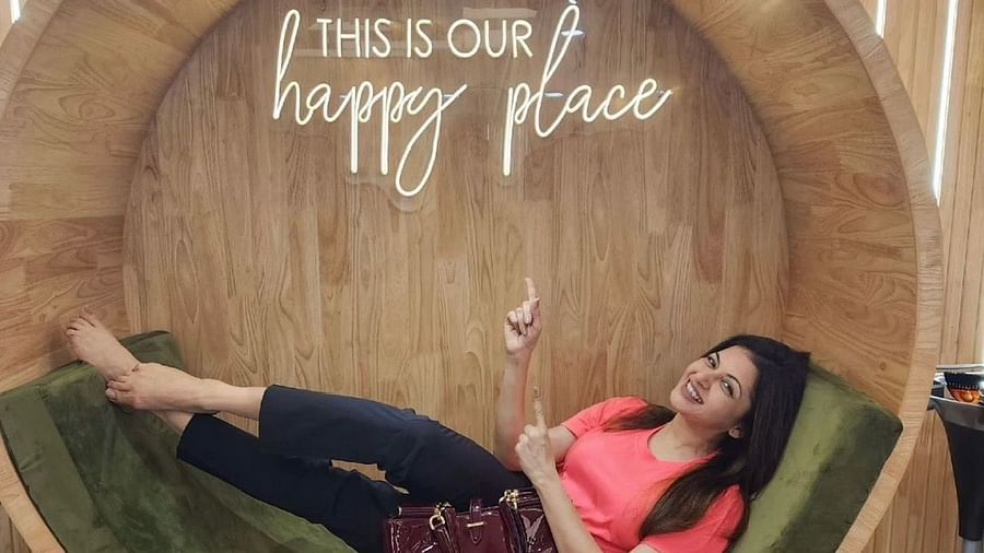 an indian celebrity posing while sitting inside a circular seating - IOSIS Spa & Wellness