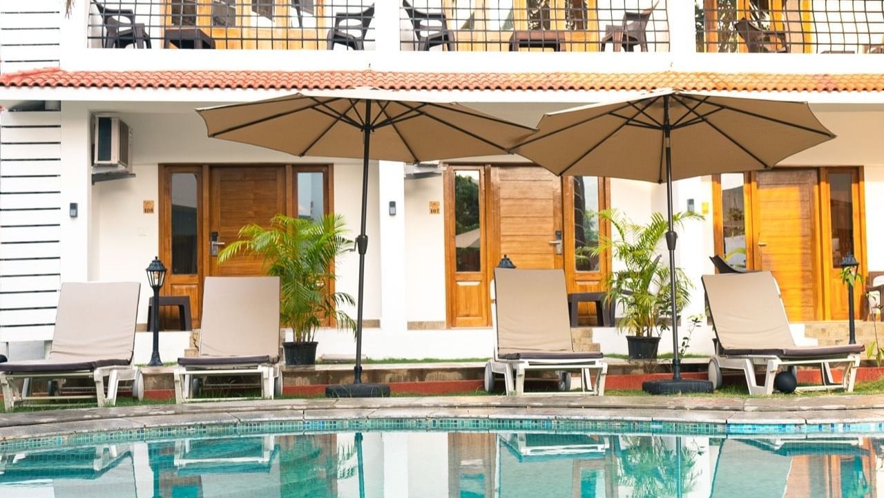White building with outdoor seating, pool  and patio.