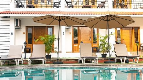 White building with outdoor seating, pool  and patio.