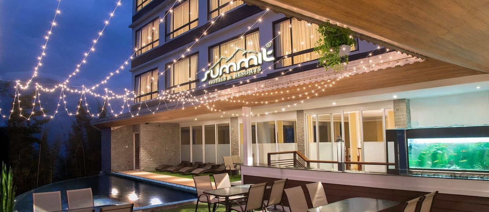 A pool side dining arrangement illuminated by hanging lights - Summit North Star, Gangtok