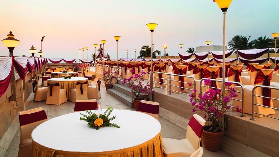 An image of the rooftop banquet hall with round tables, chairs and beautiful decoration - Ramada Plaza by Wyndham Palm Grove