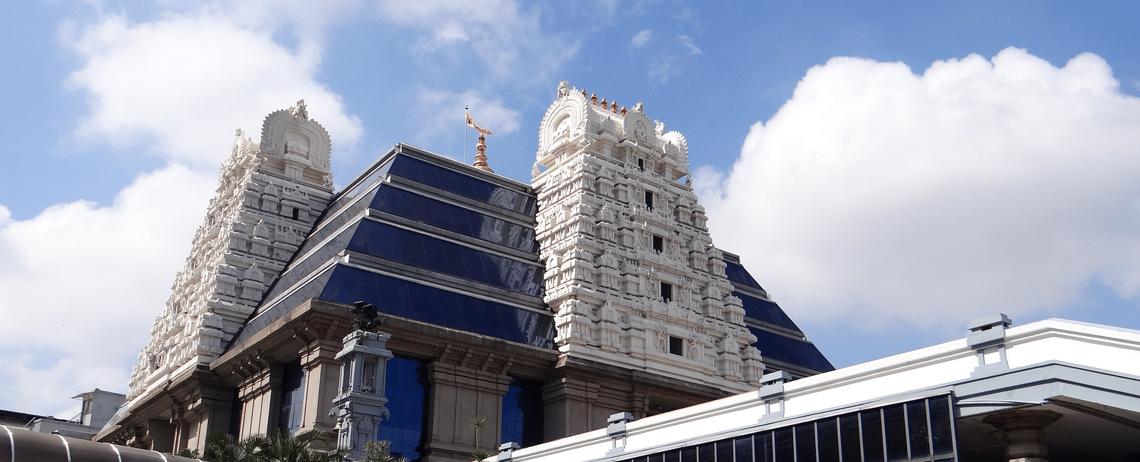 An overview of ISKCON temple in Indore with white clouds on blue sky in the background.