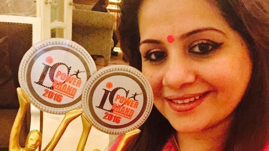 Kiran Bawa posing for a picture with two awards - IOSIS Spa & Wellness