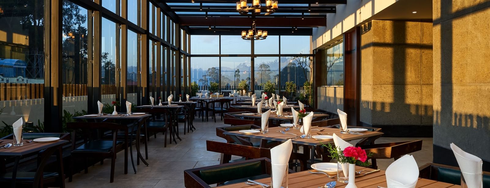 A rooftop dining view with variously arranged seating under an ambient lighting at The Hamuse Hotel, Kodaikanal.