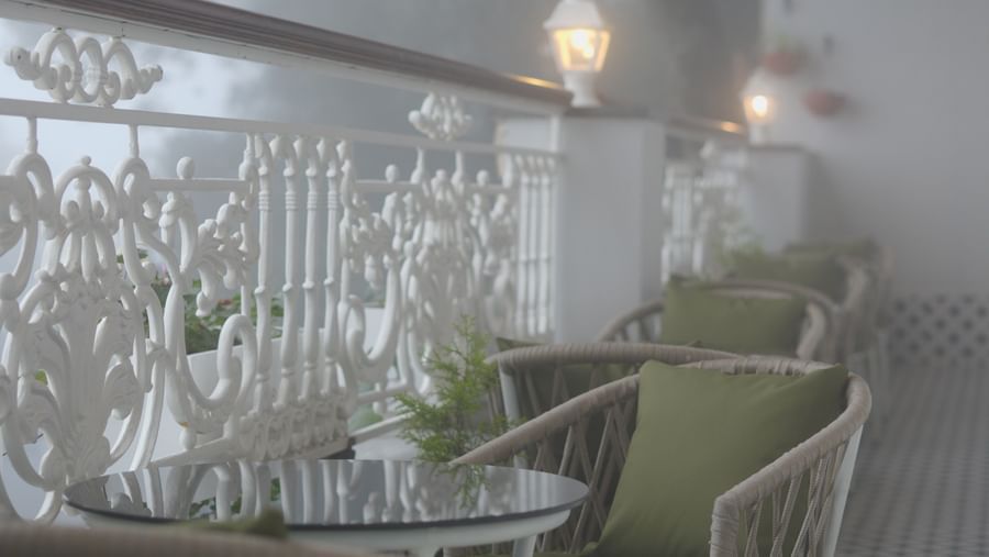 Outdoor dining setup with cushioned chairs and foggy views through the railing - Mayfair Cafe & Suites, Dalhousie