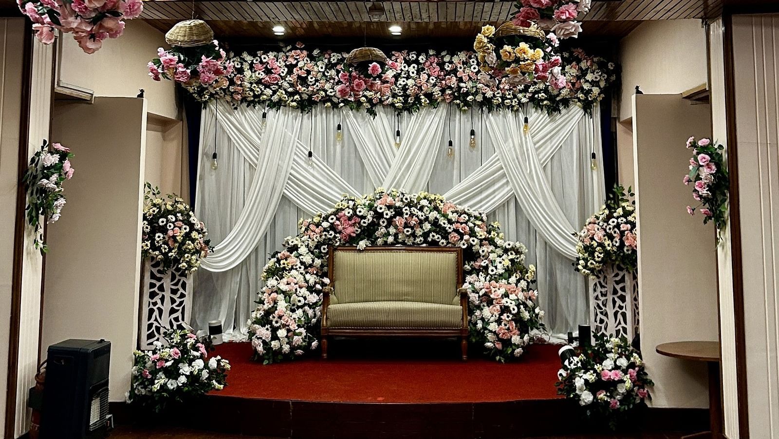 Floral ceiling decor with backdrop setup for wedding ceremony at Cedar Inn, Darjeeling, in an indoor event space.