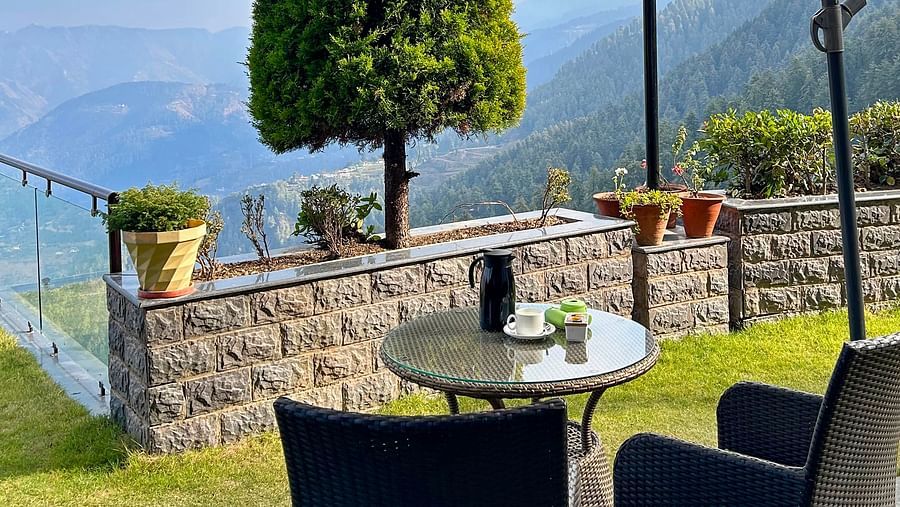 Outdoor dining under a large umbrella with panoramic mountain views at Aranya Himalayan Retreat, Mashobra