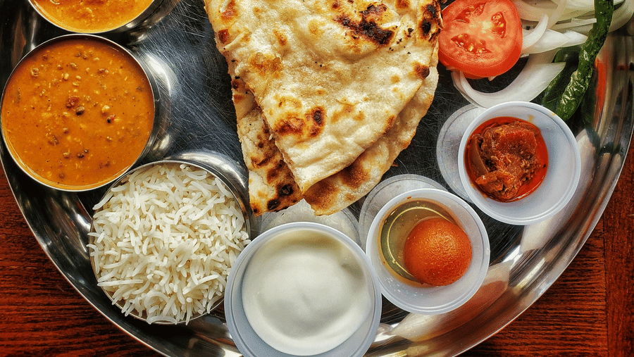 A neatly arranged plate with several Indian delicacies served.