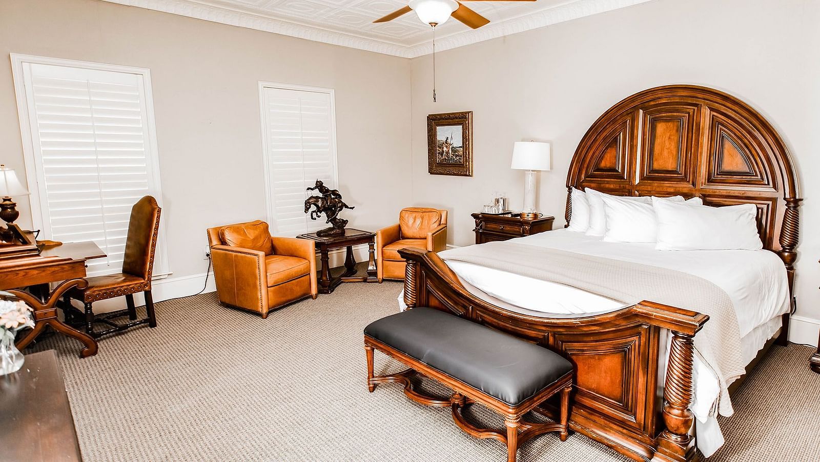 A traditional bedroom featuring a wooden bed, elegant decor, and a ceiling fan, providing a comfortable and timeless space - The Grand Hotel & Ballroom, McKinney