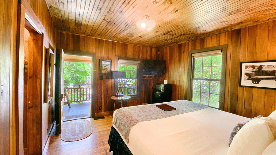 a beautiful image of a bedroom with wooden interiors with a double bed in the middle of the room - Historic Tapoco Lodge