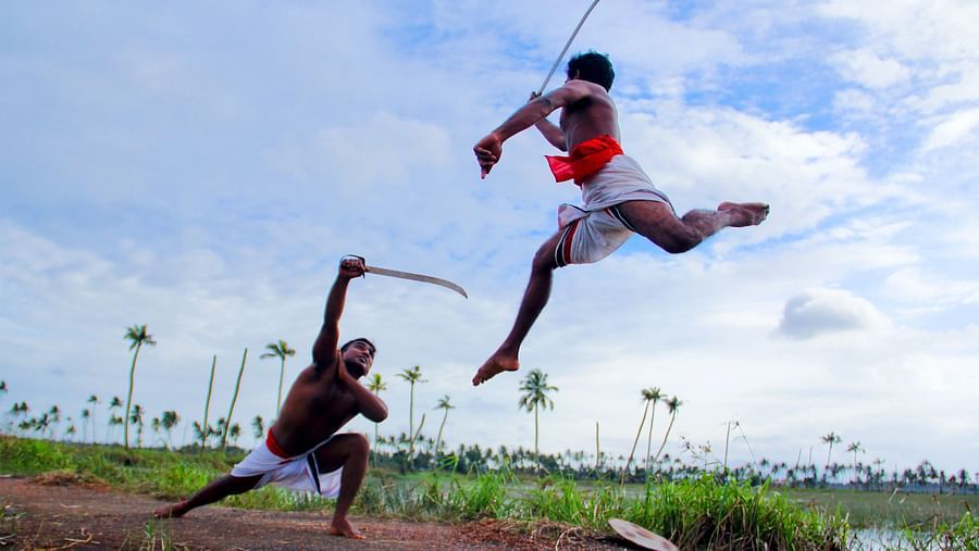 Two men demonstrate Kalaripayattu, an Indian martial art in the outdoors.