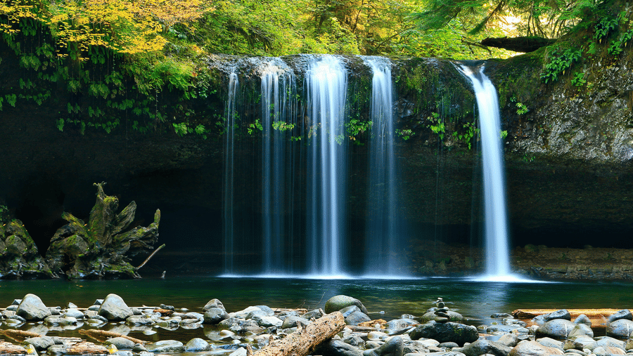 A waterfall cascading down to a waterbody with rock and nature surrounding it