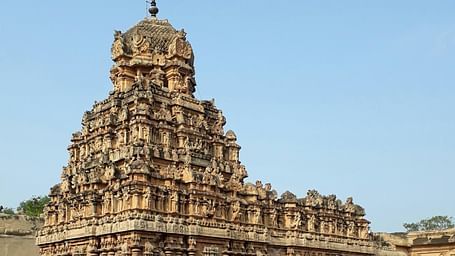 A wide view of the temple featuring intricate stone carvings on the top, showcasing detailed architectural design