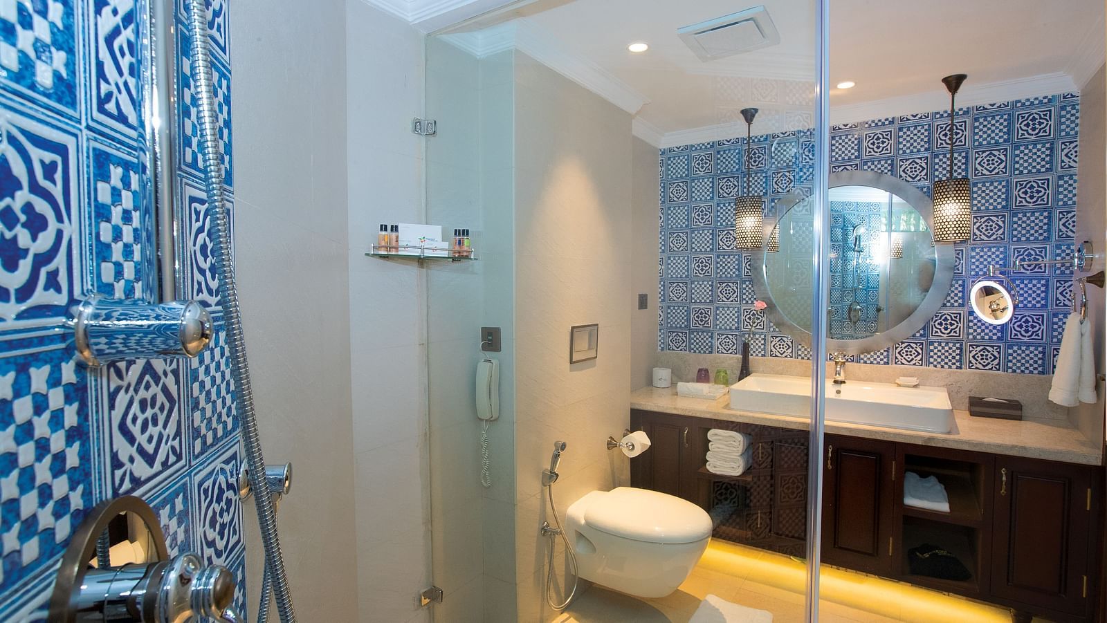  Bathroom with a mirror above the washbasin, separate lighting for it, and a glass partition separating the shower area