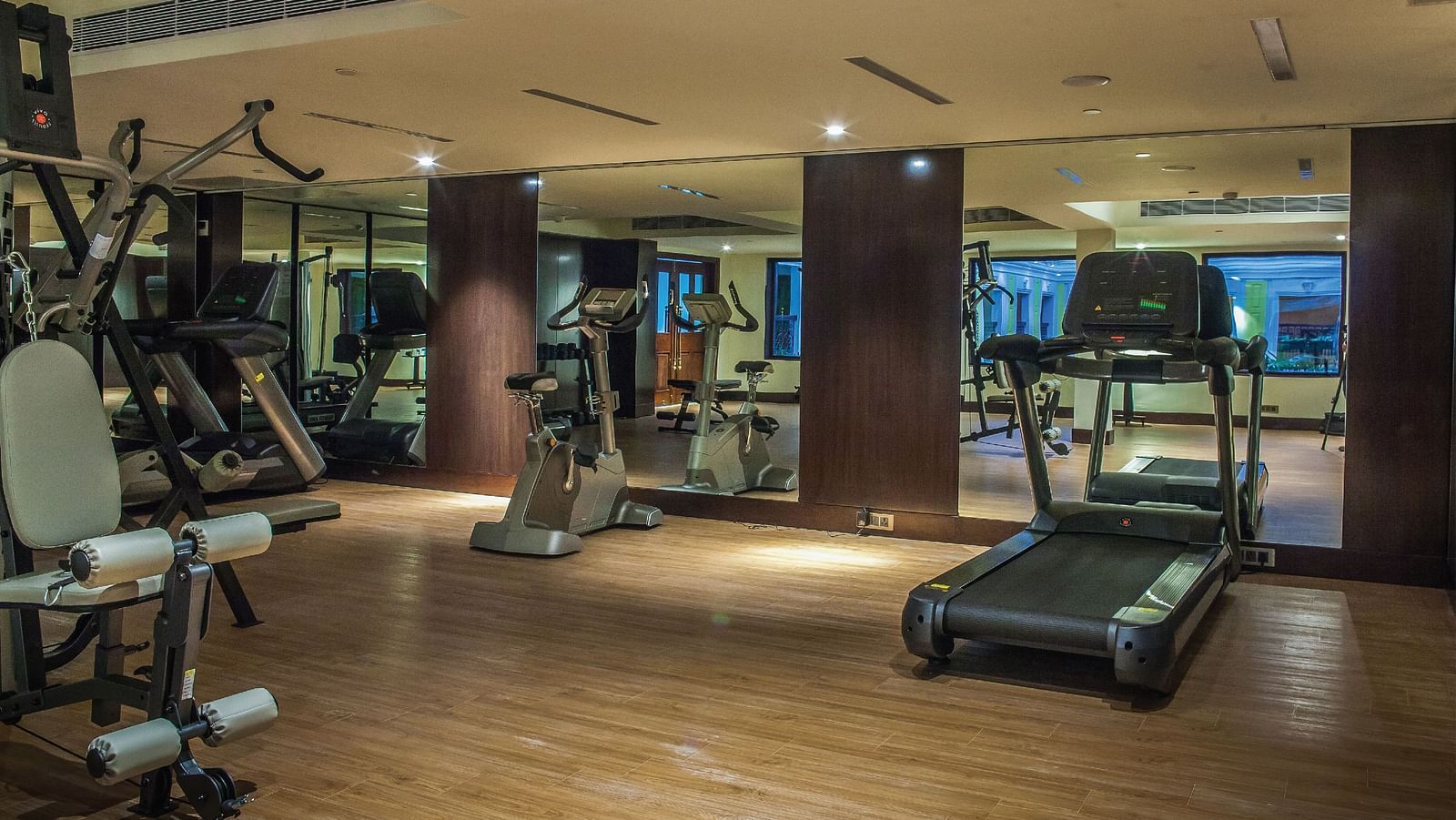 Gym with all the equipment neatly arranged, ample space around, and mirror walls with lighting