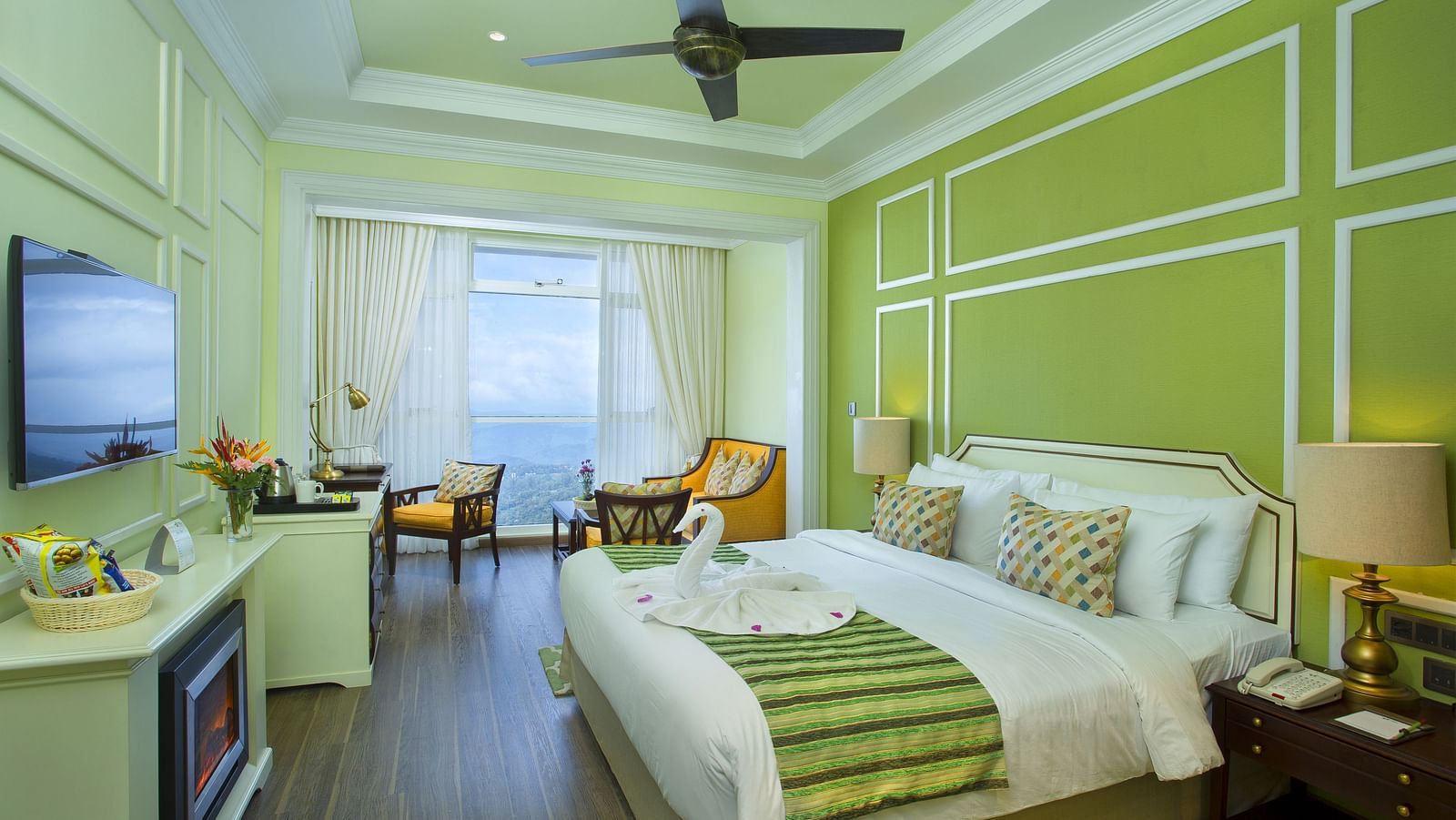  Spacious bed with furniture for seating, a bedside table, and a wall-mounted television at Fragrant Nature Munnar.