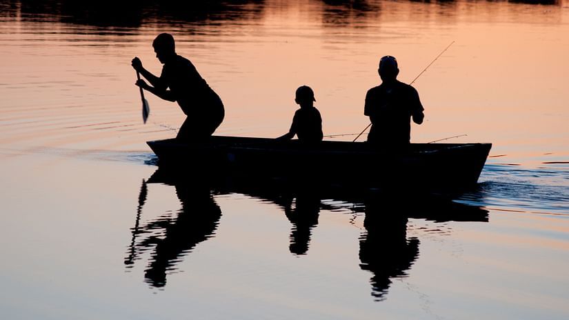 silhouettes of two adults and a child on a boat rowing to reach a destination 