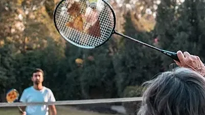 A man and a child playing with a large bubble wand in a park at Karma Chalets.