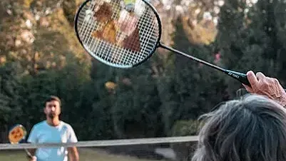 A man and a child playing with a large bubble wand in a park at Karma Chalets.