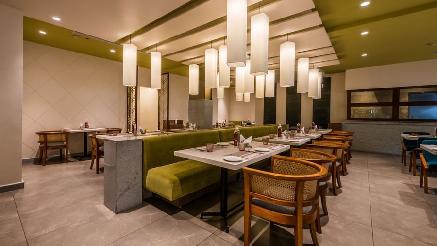 A modern restaurant area with inviting green and brown seating and unique hanging lights, ready for guests at Shilton Dee Cee.