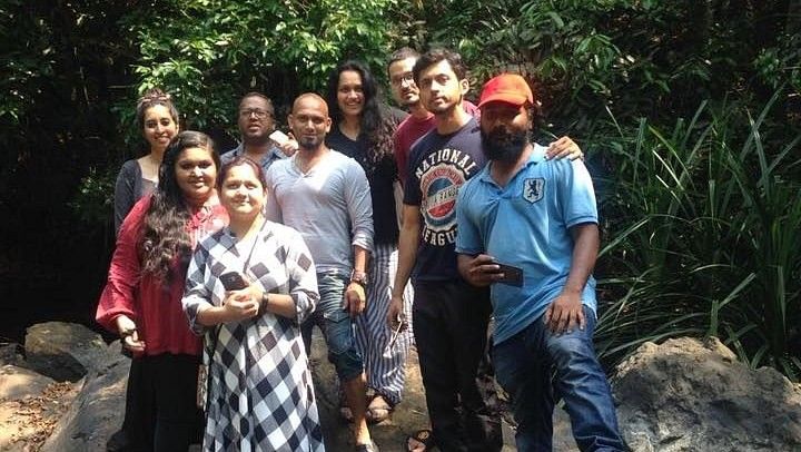 Group of people standing together on rocks in a natural setting, smiling at the camera.