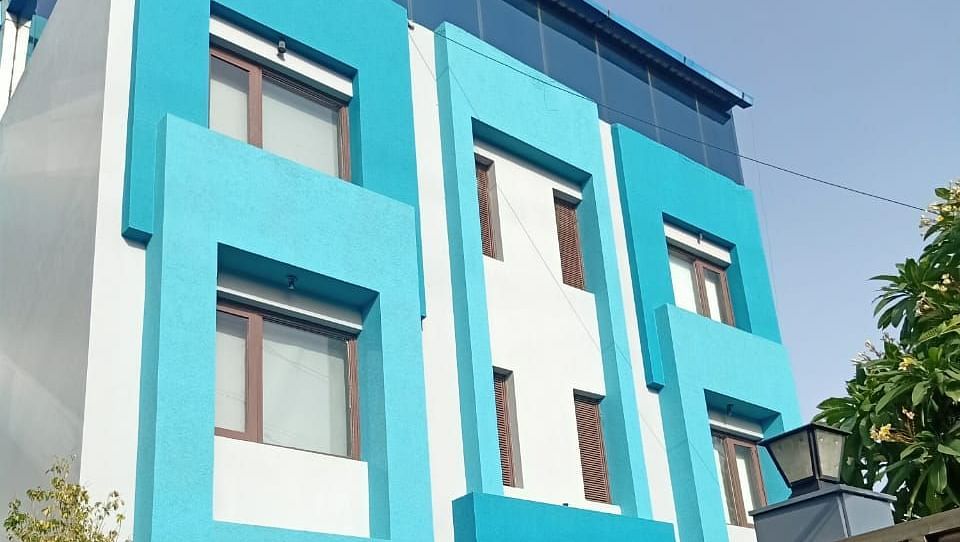 A colourful blue building with multiple windows and some greenery in front - Asian Suites IFFCO Metro, Gurgaon